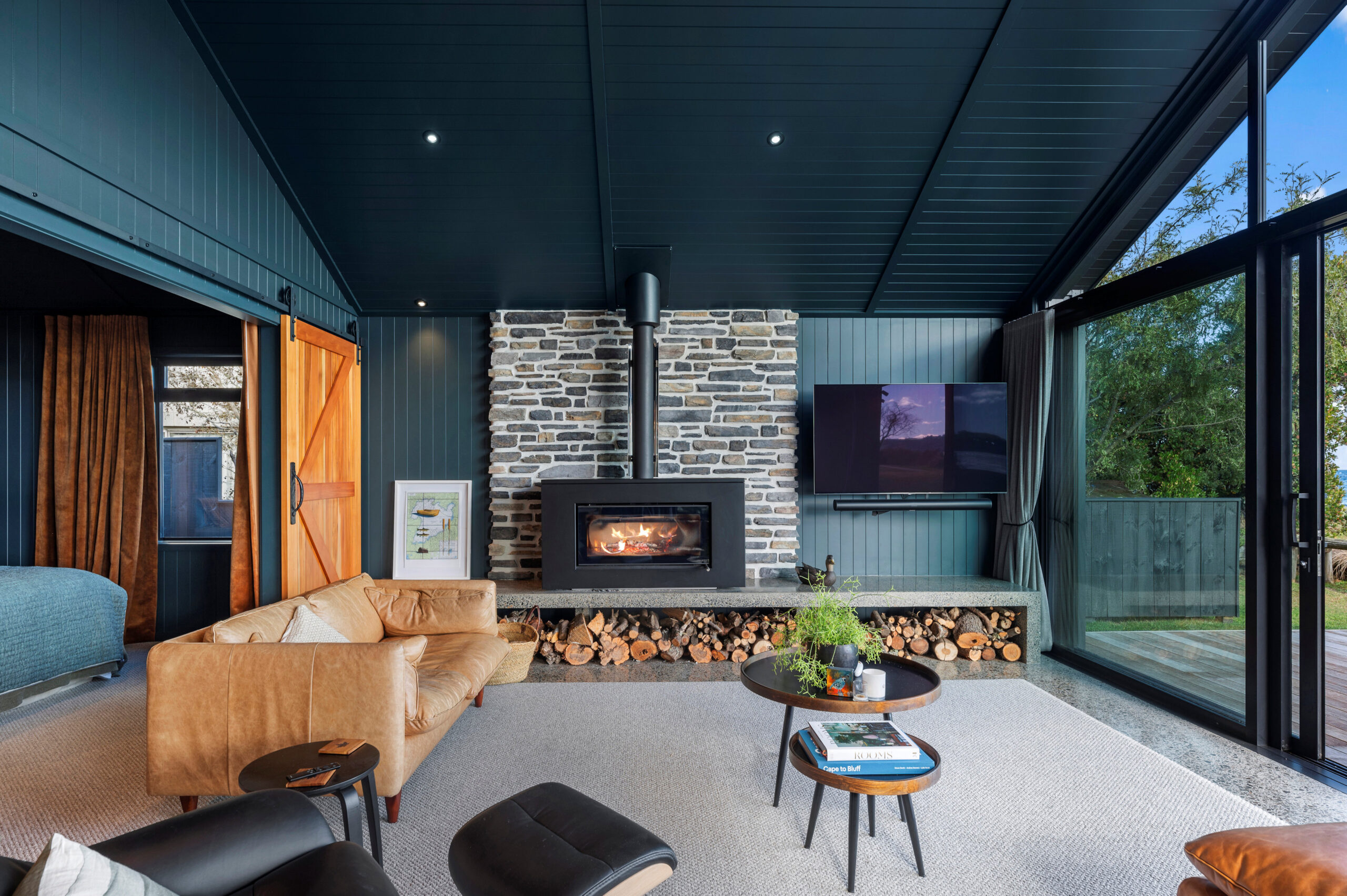 The natural elements throughout this thoughtfully designed living room, centred around the fireplace with stone wall creating a unique custom home build.