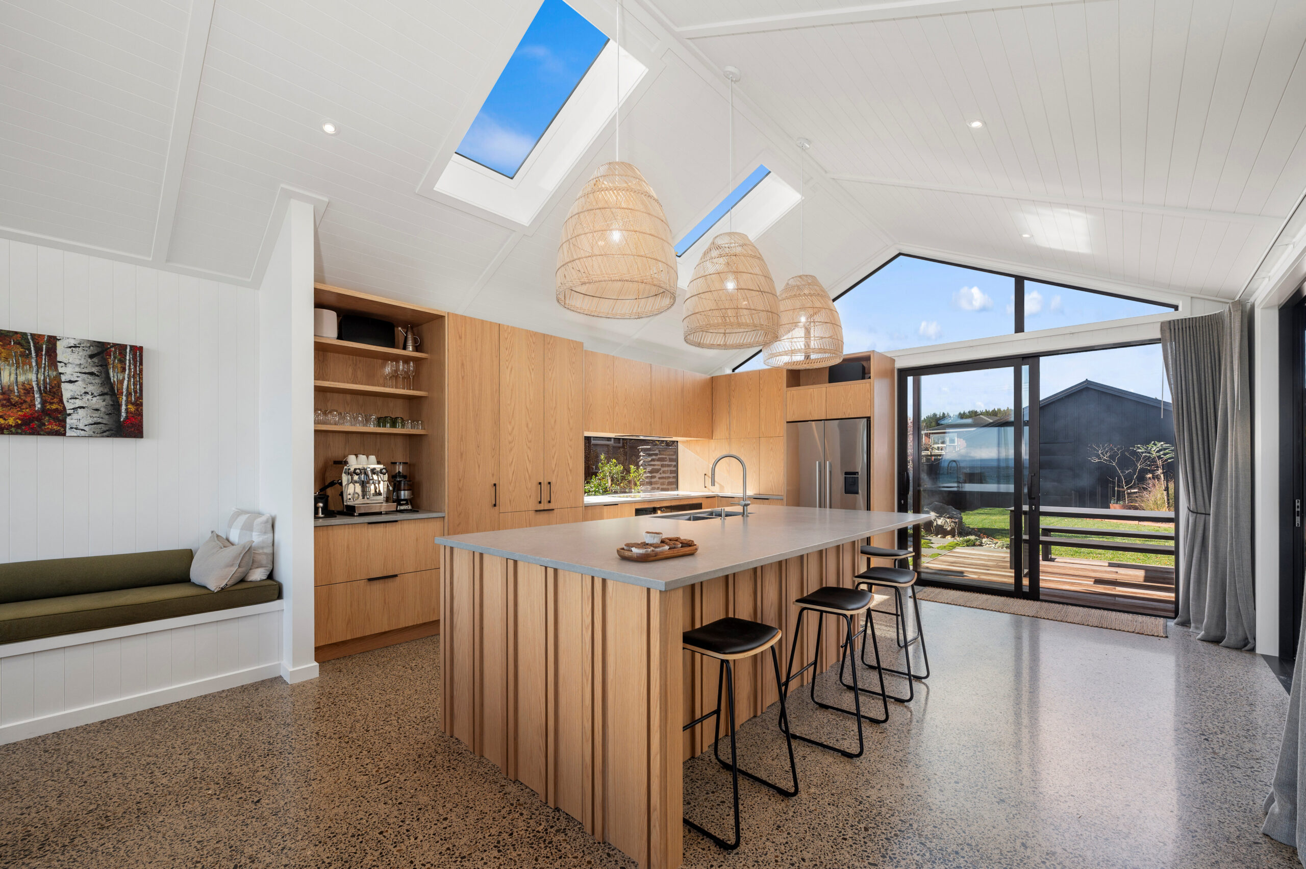 This New Kitchen features Plywood Cabinetry, vertical battens to match the exterior, engineered stone bench top, polished concrete, skylights and pendant lights to make this space natural, bright and homely. Completing the entertaining space of this new home in Taupo.